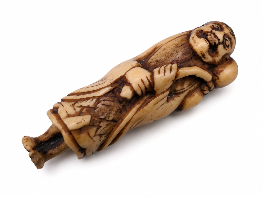 A 17th/18th century Japanese carved stag horn netsuke: Dimensions: Height 7 cm. Description: A 17th/18th-century Japanese carved stag-horn netsuke of a sage. The reclining figure is sensitively worked along the natural curve of the horn, with the warm pat