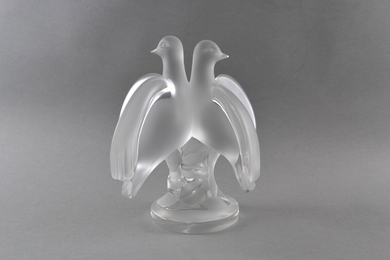 Lalique France, Ariane Crystal Double Doves Figurine: Model Number 11638, frosted glass doves over clear round base, signed (at base): Lalique, retains original model number sticker at base, H: 8 1/4", w: 7", d: 4 3/4"