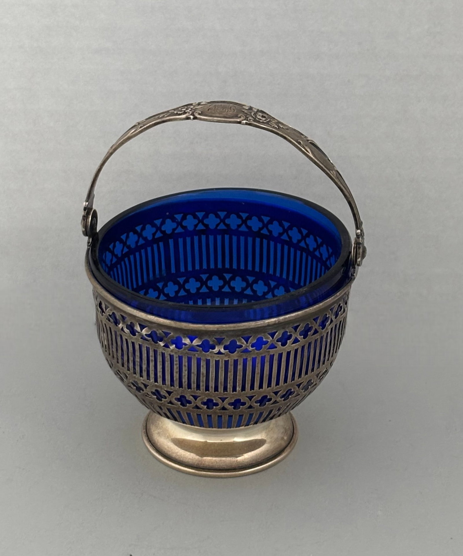 Sterling Silver And Cobalt Glass Sugar Basket, Late 19th-Early 20th Century: Reticulated allowing blue glass to show through with monogrammed handle; marked sterling and numbered 3747; 2.3 OZT; H: 2 3/4 x dia: 3 inches