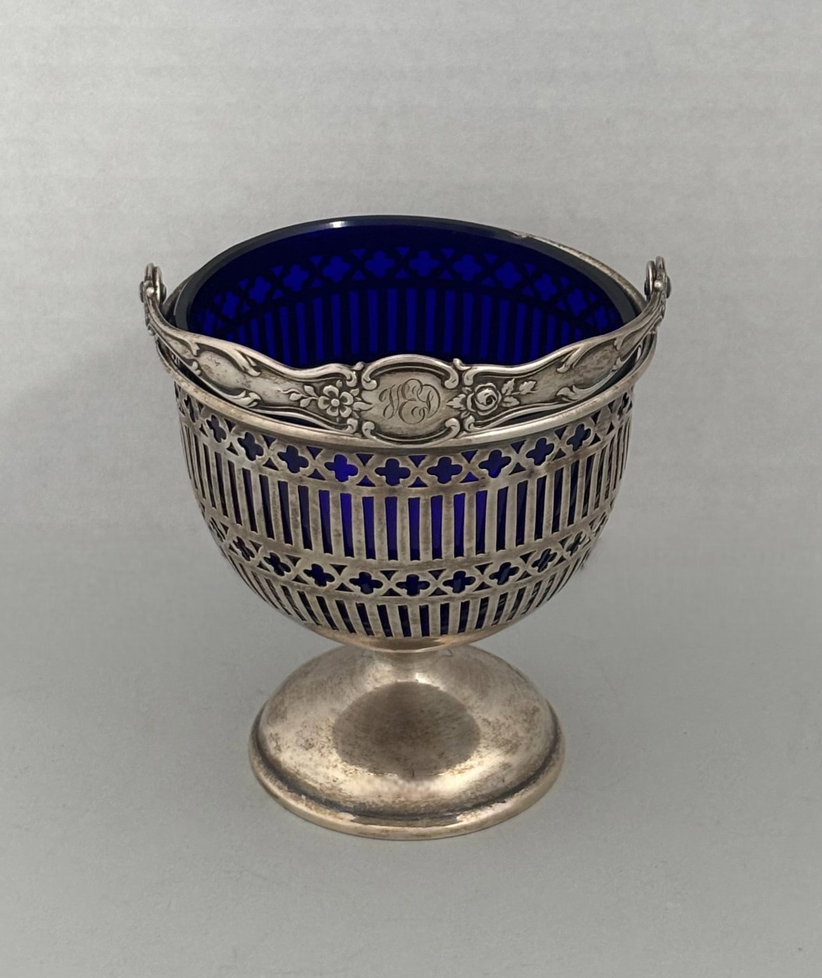 Sterling Silver And Cobalt Glass Sugar Bowl, Late 19th-Early 20th Century: reticulated allowing blue glass to show through with monogrammed handle; manufacturers mark sterling and numbered 3747; 2.9 OZT H: 3 3/4 x dia: 3 1/2 inchesCONDITION: one small minor chip to edge of g