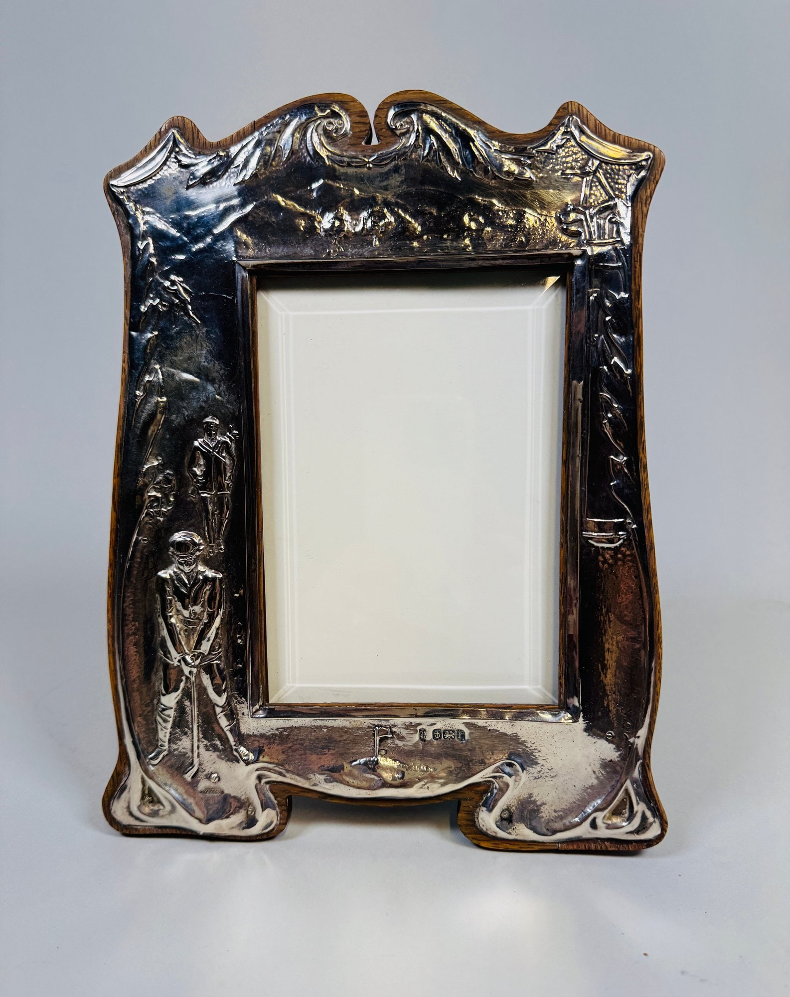 English (Birmingham) Art Nouveau Sterling Silver Picture Frame, 1905: The silver facing mounted to stained wood frame with hinged support, golf-themed decoration, Birmingham hallmarks, H: 9 1/2 x w: 7 inches (overall), H: 4 x w: 6 (opening)