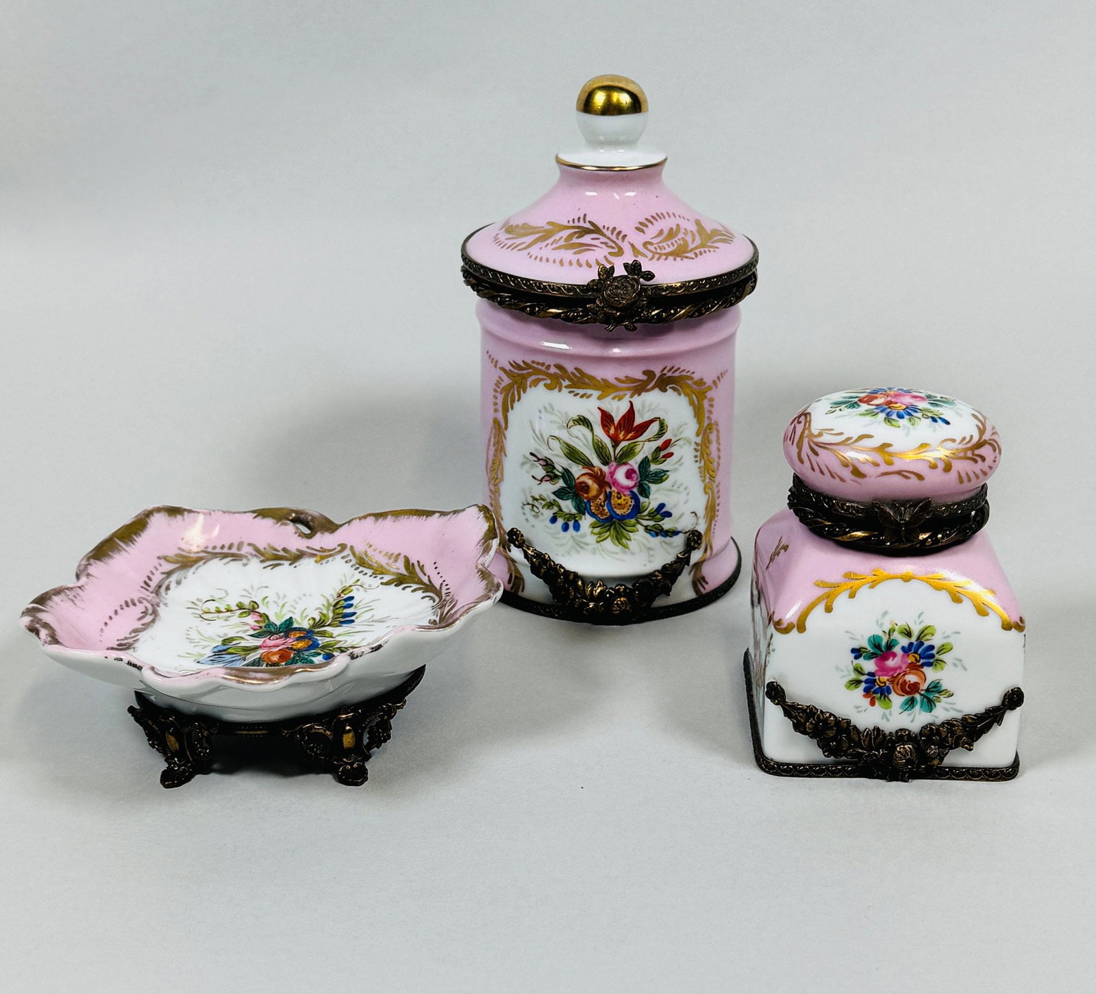 Vintage Limoges Porcelain Peint Main Vanity Set (3): consisting of a cylindrical covered box and trinket dish together with an associated inkwell of similar style and color; the box h: 5 1/2 x dia: 3 inches CONDITION: light wear to gold painted edge on