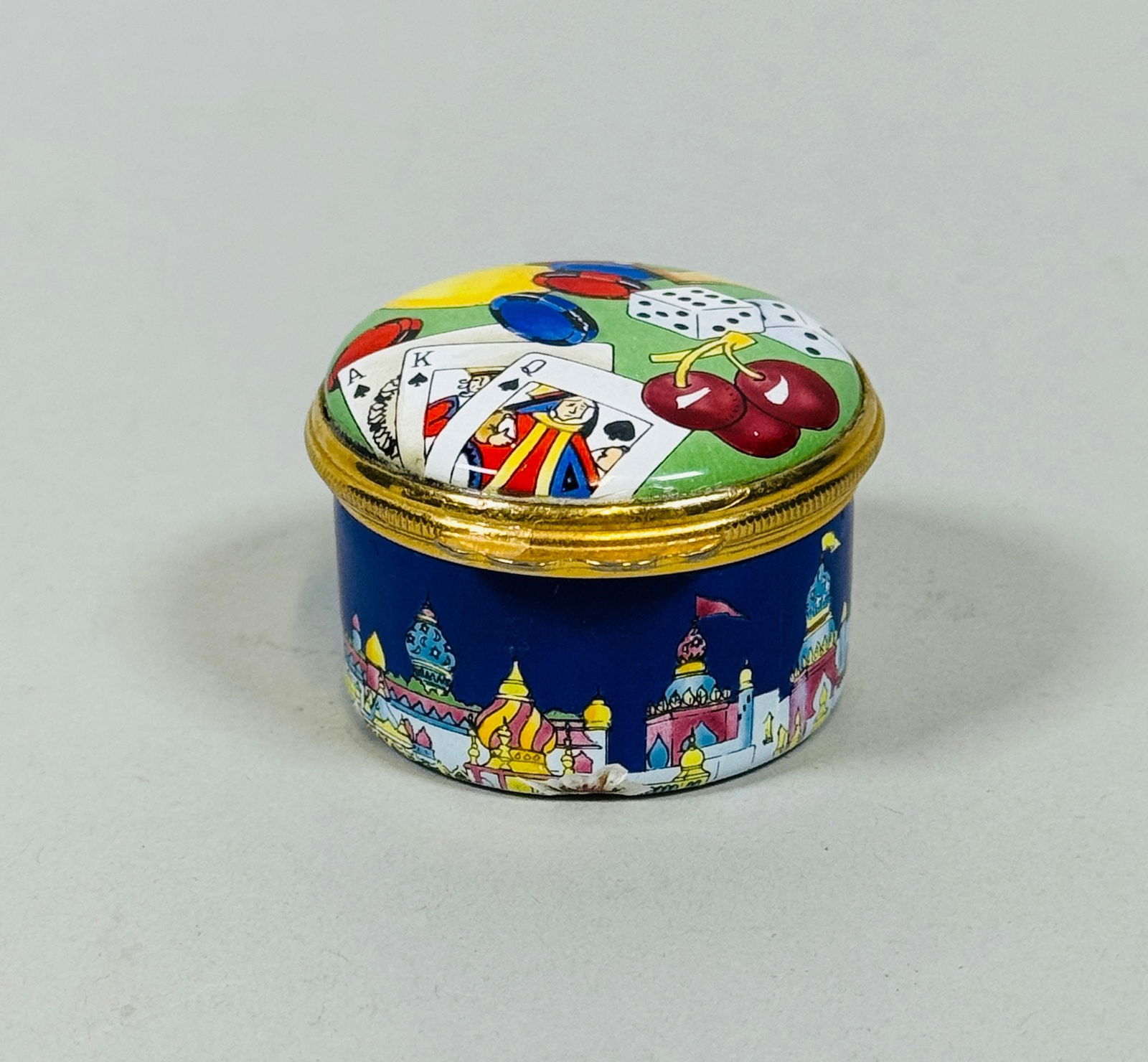 Halcyon Days Enamels Casino Themed Pillbox - Designed By Tiffany And Co: H: 1 inch x diameter: 1 1/2 inchesInterior of the lid features an image of a slot machineCondition: serious chipping along the base rim