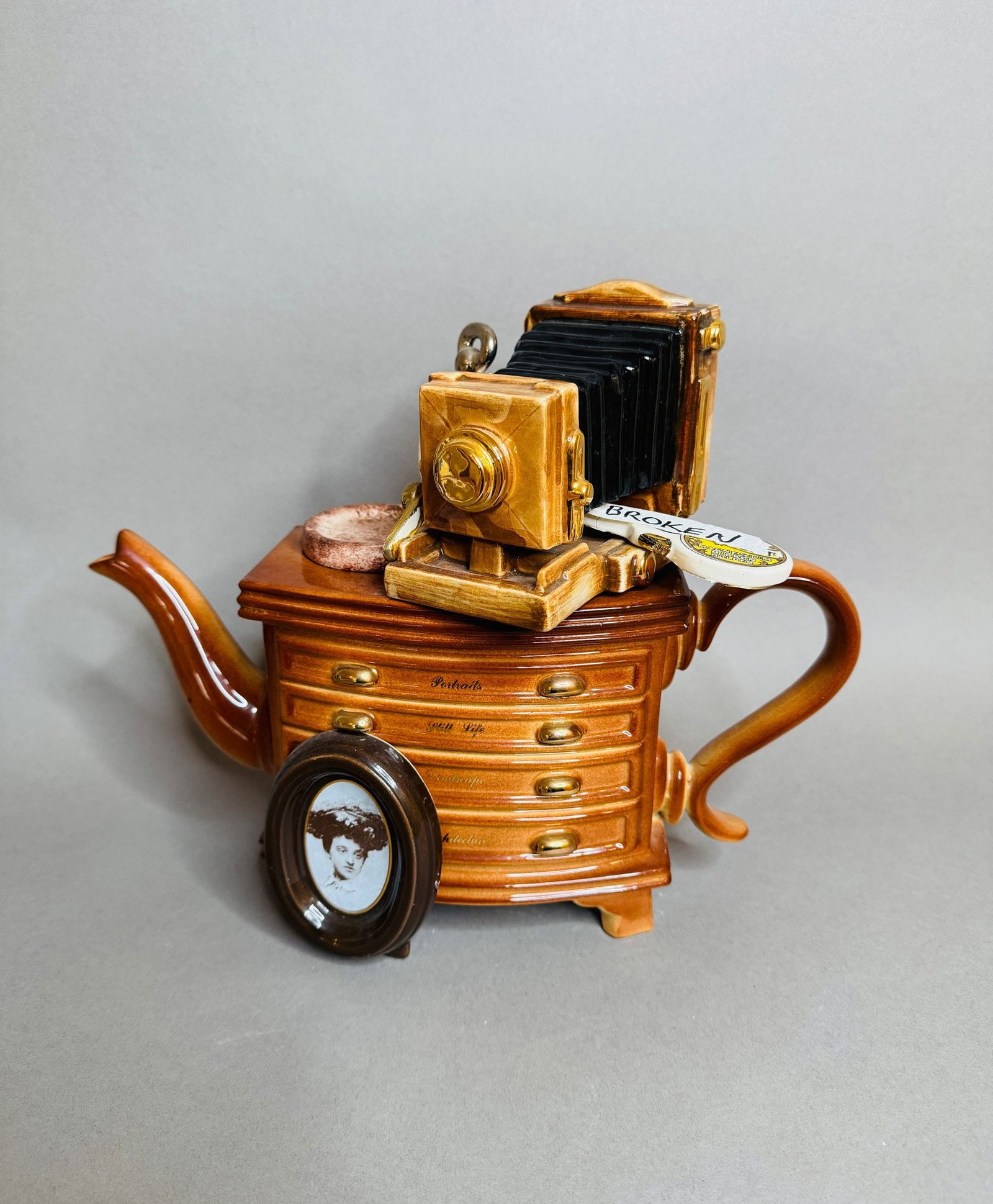 Richard Parington Designs Photographer Table Collectable Teapot: H: 10 inches x w: 12 1/2 inches x d: 3 1/2 inchesMade in Kent EnglandCondition: one ornamental piece of photography equipment is shattered into three pieces