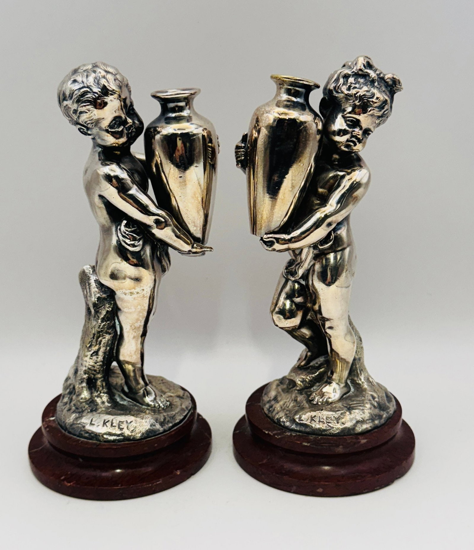 Louis Kley (French, 1833-1911) Pair Of Silvered Bronze Children With Vases On Marble Bases, C. 1900: molded signature to base of each Height: 6 1/4 inchesCONDITION: silvering in good condition areas of restoration to marble bases