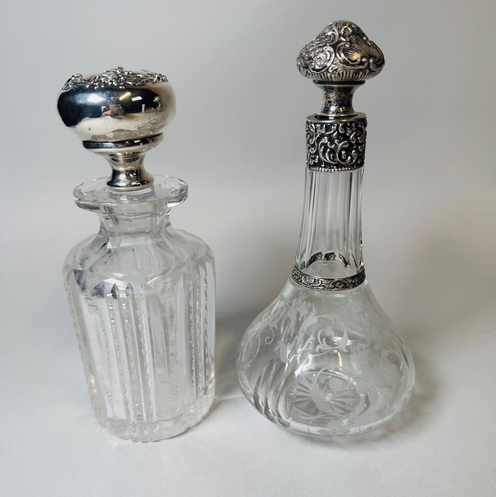 Two Silver Mounted Decanters And Stoppers (2): One stopper marked sterling at neck taller h: 8 x dia: 4 inchesCONDITION: one of the stoppers is not original to the bottle