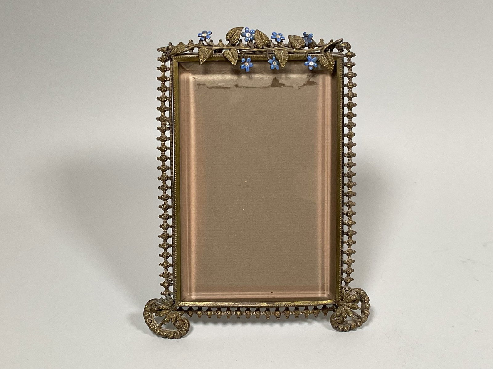 Belle Epoque Enamel And Gold Tone Filagree Easel-back Frame: H: 8 x w: 6 inches (overall); h: 6 1/8 x w: 4 inches (opening) CONDITION: top right corner is slightly off true
