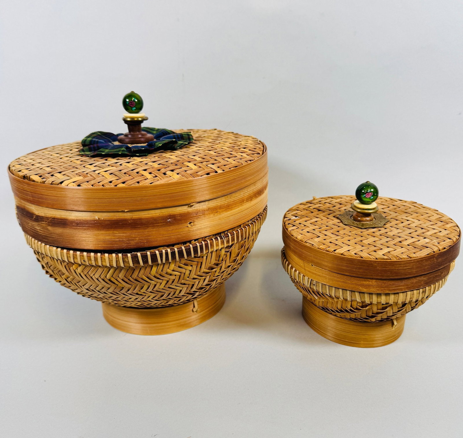 MacKenzie Childs Rattan Lidded Baskets (2): Large: H: 7 x dia.: 10 inchesSmall: H: 4 1/2 x dia.: 6 inchesCONDITION: small scratches on rim of large basket