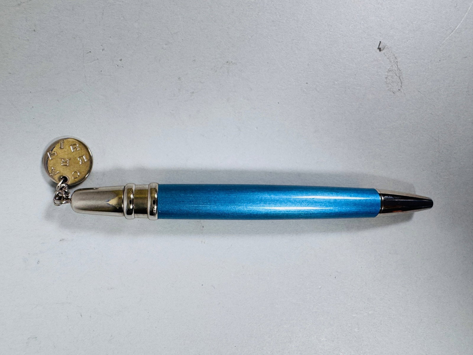 Cartier Mini Diabolo Blue Lacquer Ballpoint Pen: with dangling Cartier charm and platinum finish details 4 inchesCONDITION: excellent