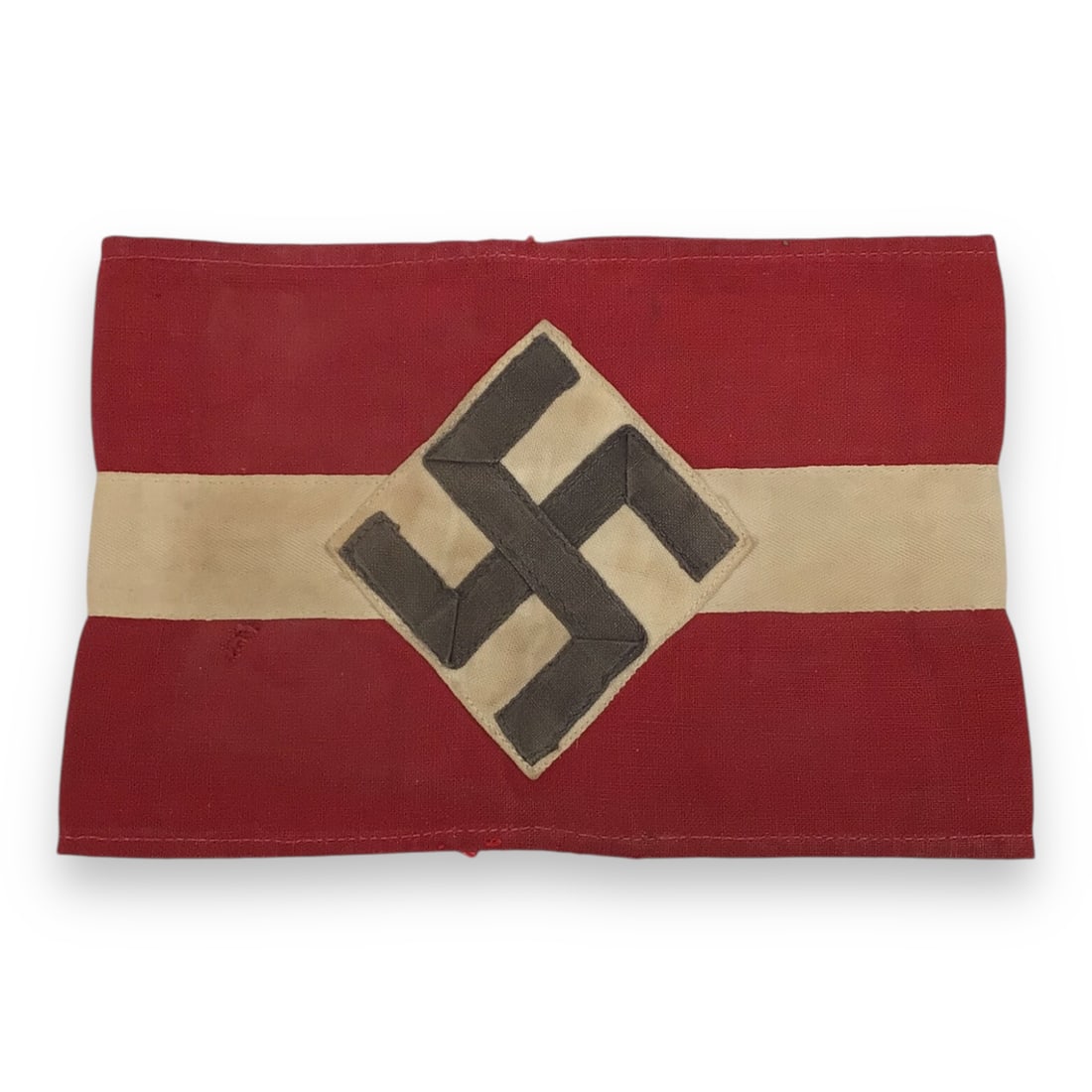 German WW2 Hitler Youth Cloth Armband: This Hitler Youth Armband is an early, multi-piece construction made of high-quality wool, reflecting the craftsmanship of pre-war NSDAP regalia. It features the traditional red band with a white circ