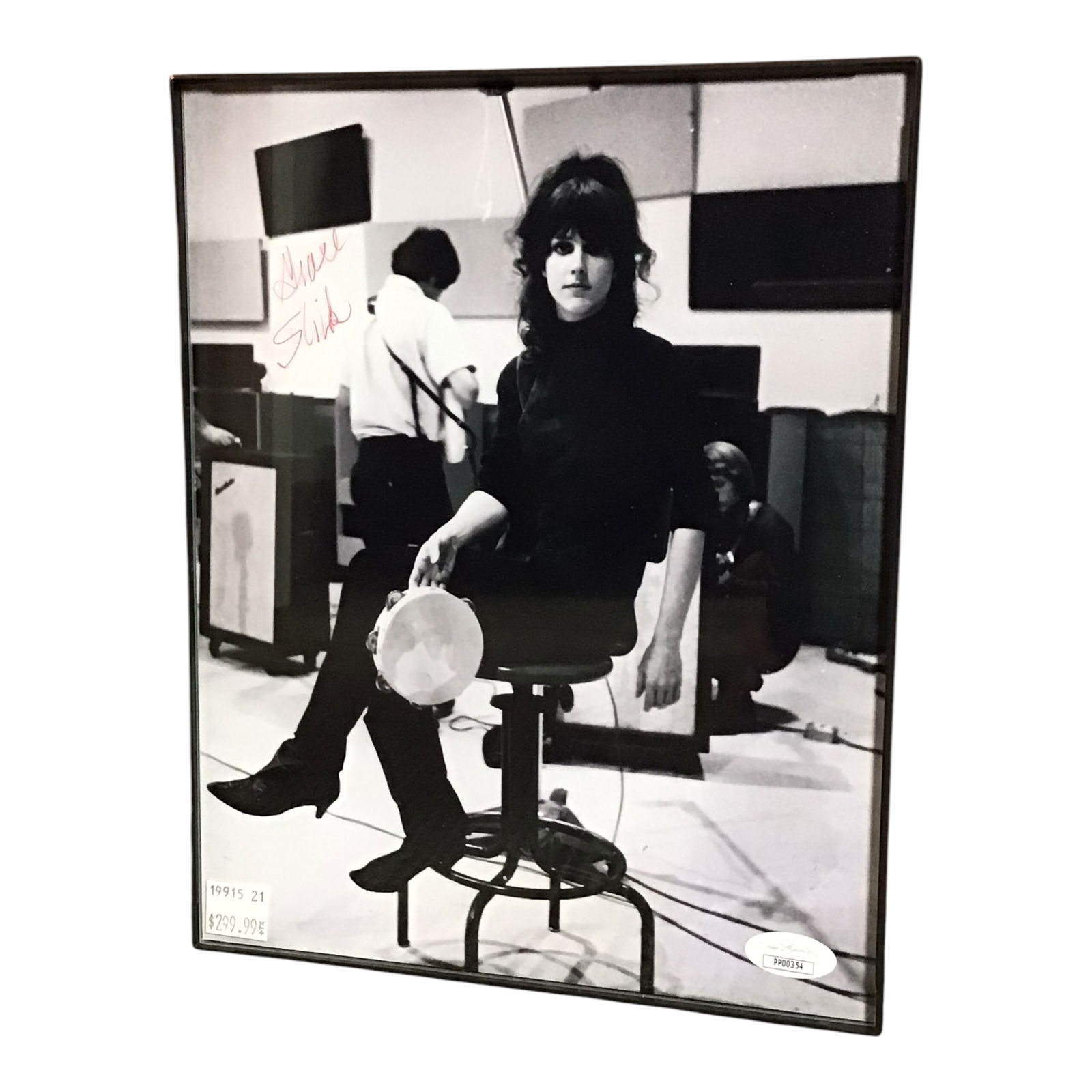 Grace Slick Signed Photograph - Framed, JSA Authenticated: Here is a powerful black-and-white portrait of Grace Slick, legendary lead vocalist of Jefferson Airplane, signed boldly in red ink. The photo captures her seated with a tambourine in hand and comes p