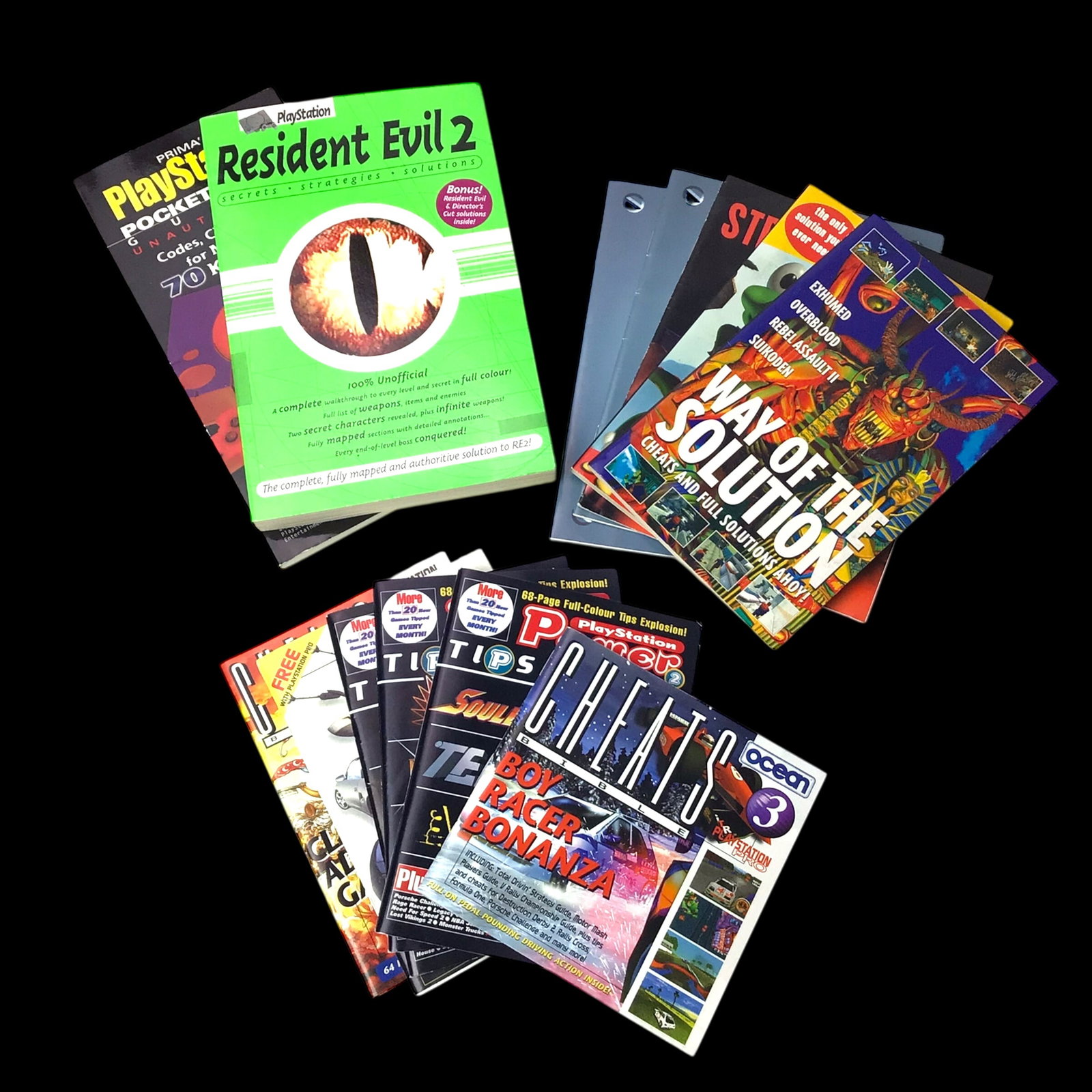 Collection of Vintage PlayStation Game Guides & Cheat Books - Resident Evil 2, Cheat Bibles, & More: Lot of original PlayStation-era guides and cheat books including the official Resident Evil 2 strategy guide, PlayStation Power Tips Bible, and several volumes of the Cheats Bible series. These items 