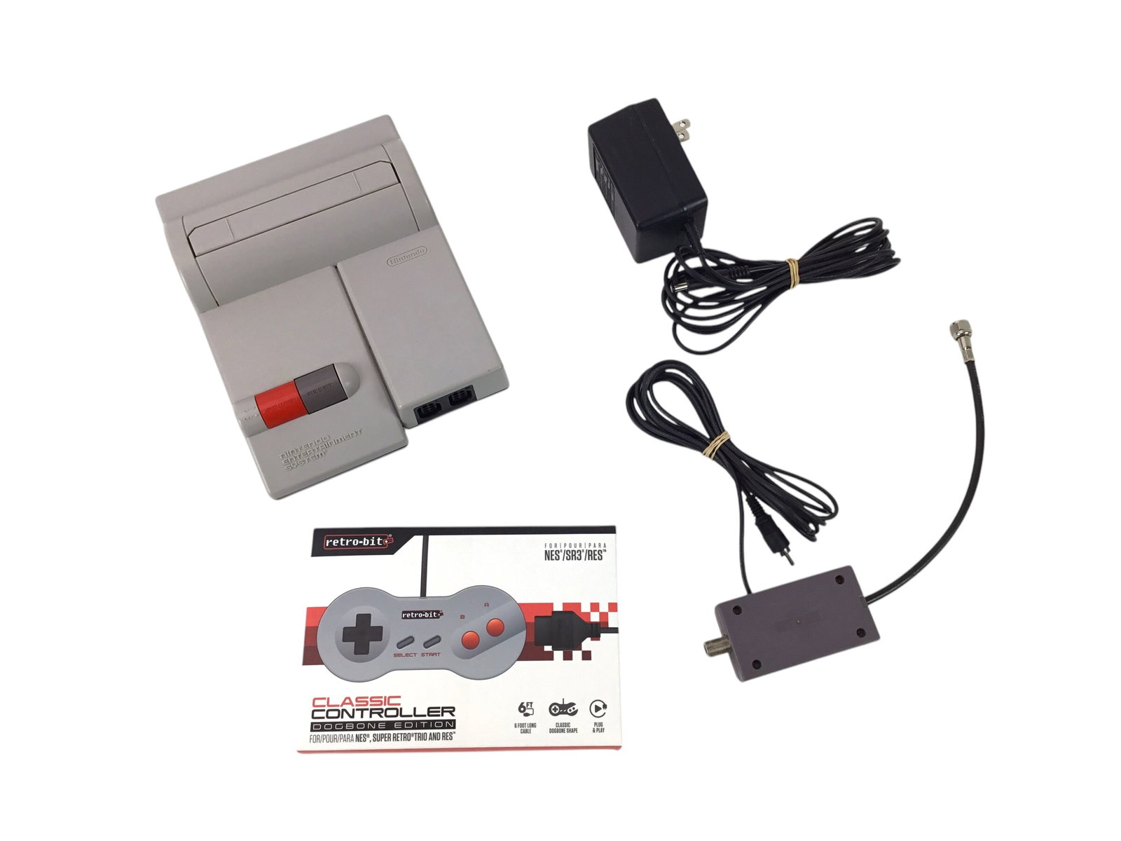 Nintendo New-Style NES Console with Sealed Retro-bit Controller - Tested, Not Functional: Compact, top-loading Nintendo New-Style NES console first released in 1993. This lot includes the console, original AC adapter, RF tuner, and a brand-new Retro-bit controller sealed in its packaging. 