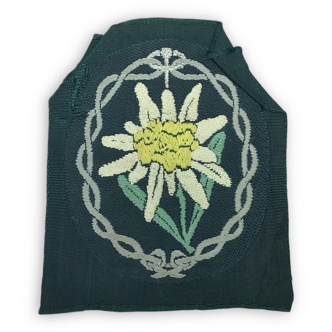 German Gebirgsjager Edelweiss Sleeve Patch | BeVo Woven, Uniform-Removed Combat WW2 Insignia: Offered here is an original World War II German Wehrmacht Gebirgsjager Edelweiss sleeve patch, manufactured using correct BeVo woven construction and removed from a wartime uniform. The patch retains