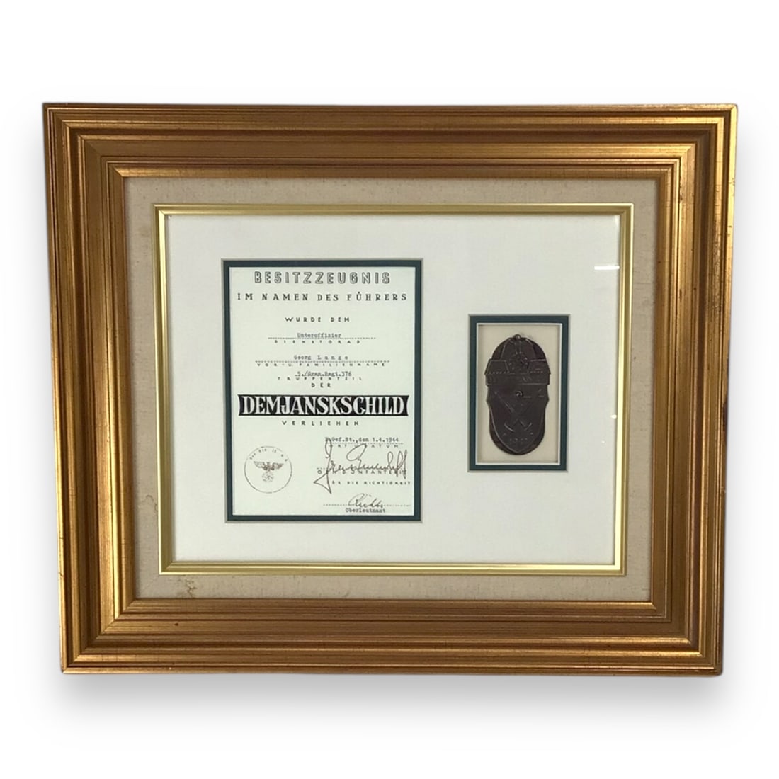 German WW2 1942 Demyansk Shield Award with Certificate named Custom Matted and Framed: An original 1942 Demyansk Shield Award and its official Award Certificate, issued to Unteroffizier Georg Lange of the 5./Grenadier Regiment 376. The shield, designed to be worn on the uniform's sl