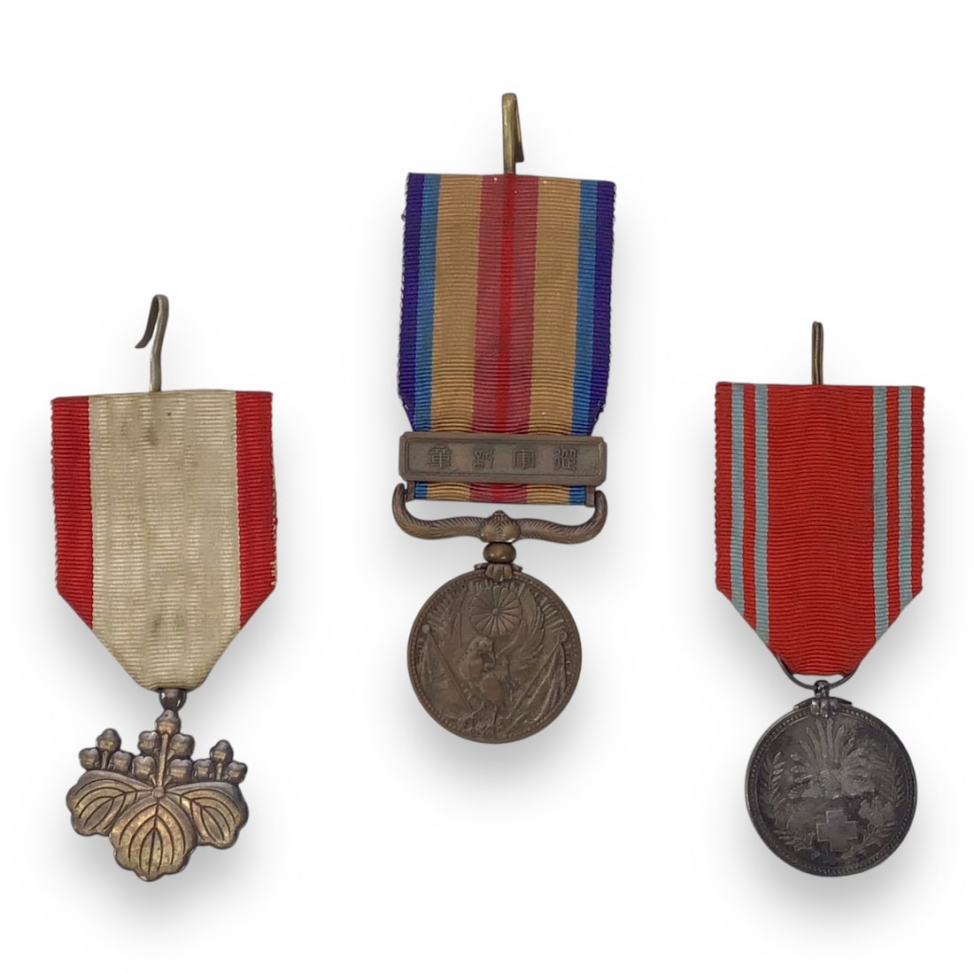 Group of Three Miniature Imperial Japanese Military Medals: This group consists of three miniature Imperial Japanese military medals, comprising a Rising Sun 7th Class, a Japanese China Incident War Medal, and a Japanese Red Cross Medal. Each miniature retains