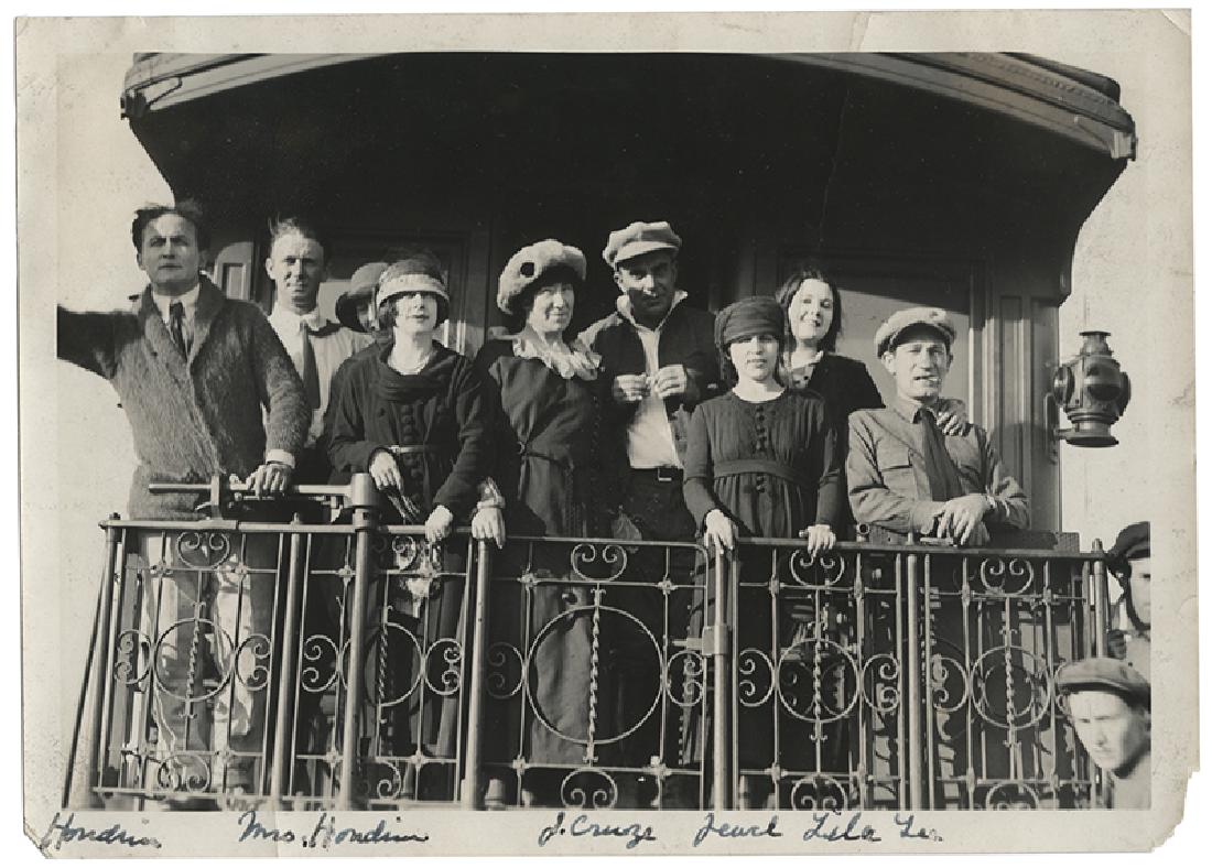 Photograph of Houdini and Company Aboard a Train Car.: Houdini, Harry (Ehrich Weiss). Photograph of Houdini and Company Aboard a Train Car. Circa 1920. Houdini and eight other individuals, including his wife Beatrice, stand on the rear of a train car. Hou