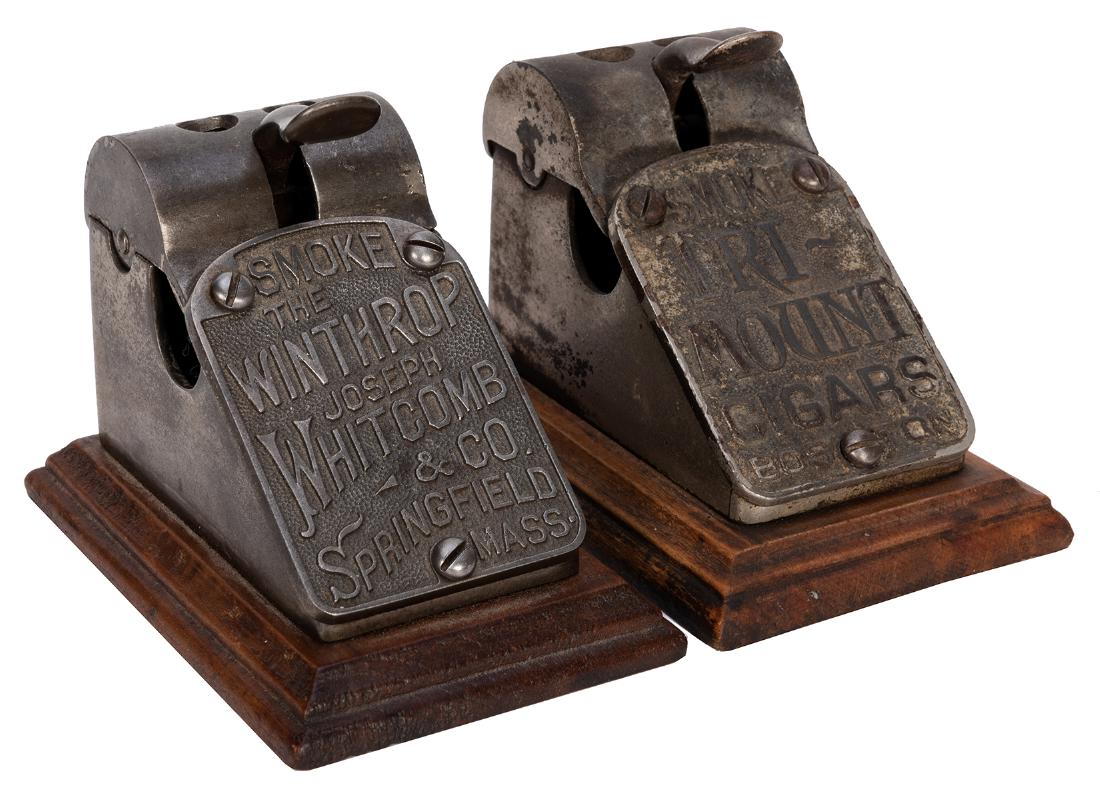 Pair of Cast Iron Cigar Cutters on Wood Base.: Pair of Cast Iron Cigar Cutters on Wood Base. Comprising: (1) Smoke the Winthrop, Joseph Whitcomb & Co., Springfield, Mass., 3 x 3”. Very good. (2) Smoke Tri-Mount Cigars, Boston. 3 x 3”. 