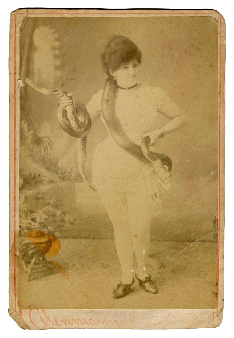 Snake Charmer Cabinet Card Photograph.: Snake Charmer Cabinet Card Photograph. New York: Eisenmann, ca. 1880s. 6 ¼ x 4 ¼". Stains and soiling, several creases.