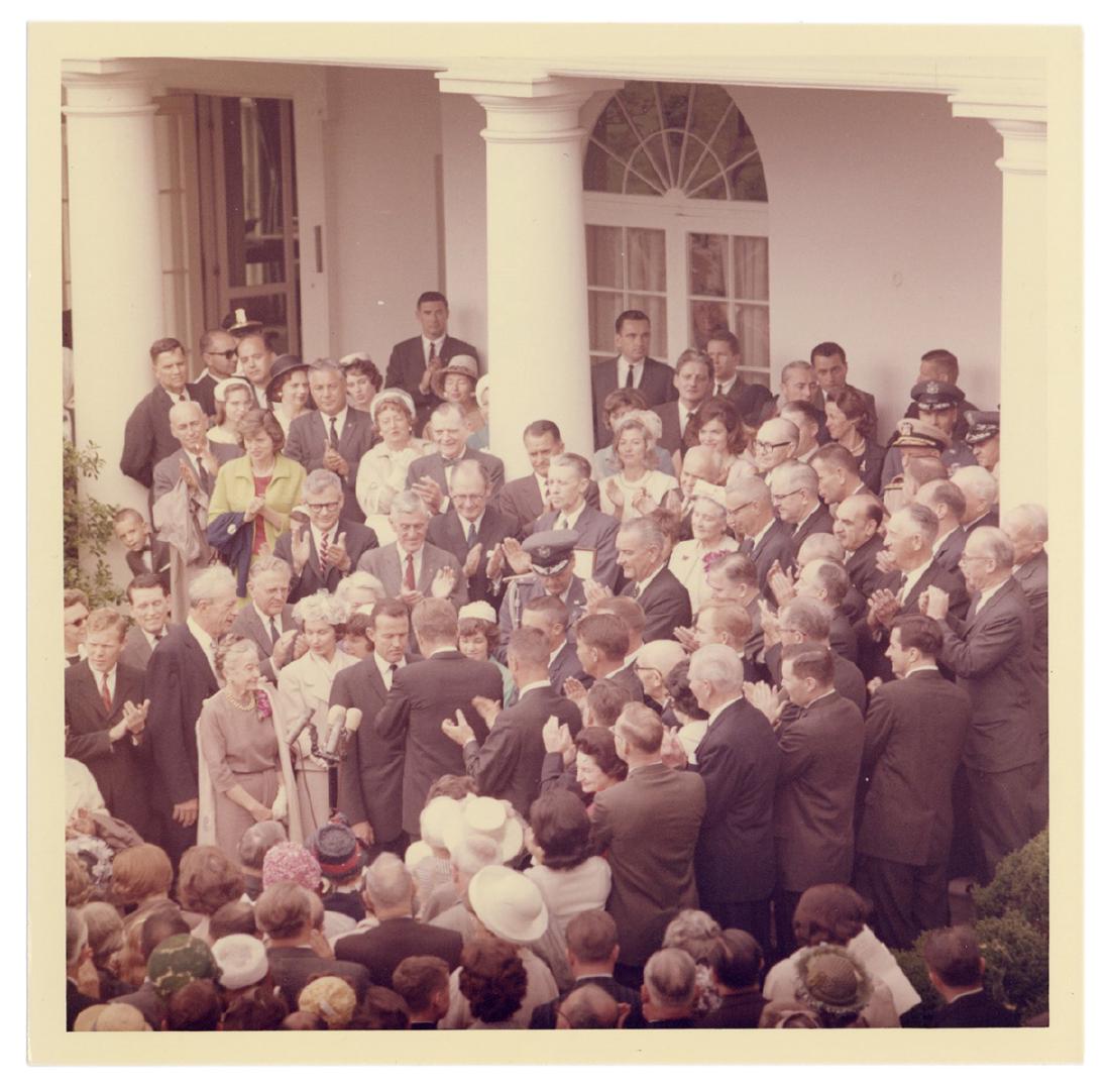 Original Photograph of JFK and Gordon Cooper.: Kennedy, John F. Original Photograph of JFK and Gordon Cooper. 1963. Glossy photograph (5 x 5”) by official White House photographer Cecil Stoughton, showing Kennedy awarding Cooper the NASA Disting