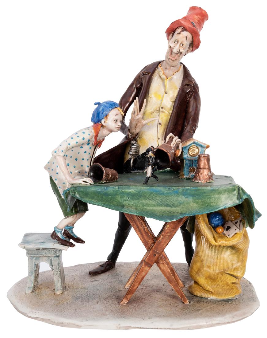 Cups and Balls Conjuring Sculpture.: Moretto, Toni (Italian, 1929—2011). Cups and Balls Conjuring Sculpture. Porcelain sculpture of a traveling magician in the act of producing a toy French soldier from a cup. A boy spectator standing