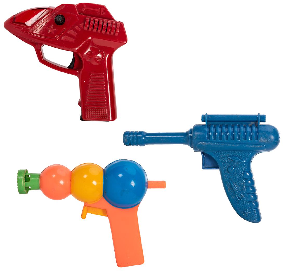 Assorted Vintage Plastic Space Toy Guns. 3 pcs. Group: Assorted Vintage Plastic Space Toy Guns. 3 pcs. Group includes a blue plastic clicker gun with space images to grip, a battery powered red plastic pistol, and a multicolored bubble gun. Largest 6 x 6&