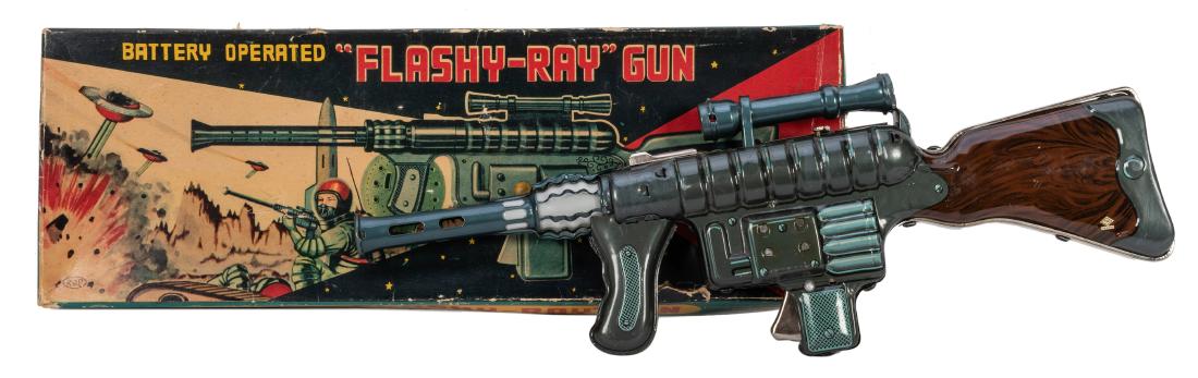 Battery-Operated “Flashy-Ray” Gun in: Battery-Operated “Flashy-Ray” Gun in Original Box. Japan: TN, 1950s. Lithographed tin and plastic rifle in the original pictorial cardboard box. A nice example with well-preserved original