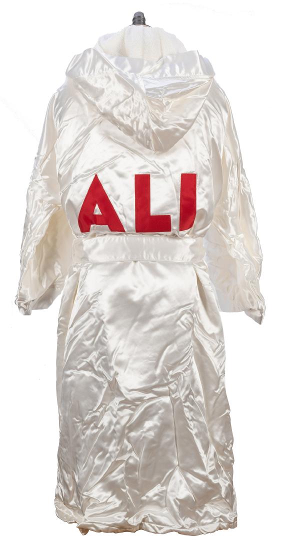 2001 Columbia Pictures “Ali” White Satin: 2001 Columbia Pictures “Ali” White Satin Robe. A full length white satin hooded robe with a terrycloth lining, “ALI” sewn in block capital red letters on the back. Size medium,