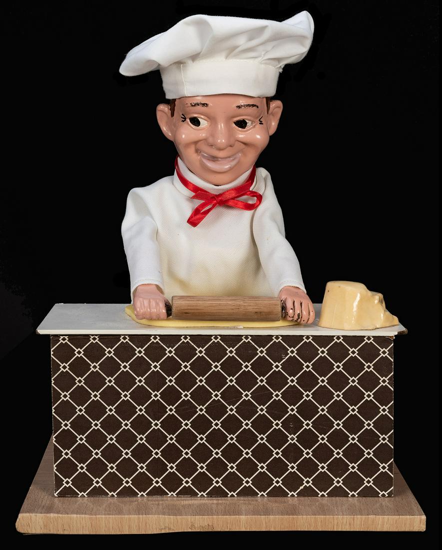 Pizza Dough Roller Electric Automaton.: Pizza Dough Roller Electric Automaton. Chef figure with ceramic hand-painted face and hands, polyester costume with hat, rolling dough on a laminate table. 11 x 9 ½ x 10”. Slight chipping to corner