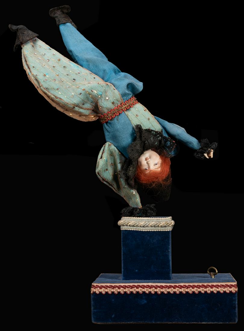 Harlequin Circus Acrobat Musical Automaton.: Harlequin Circus Acrobat Musical Automaton. Possibly by Reuge, depicting a harlequin doll with porcelain face, cotton costume with gilt thread and rhinestones, felt boots and lace cuffs, performing an