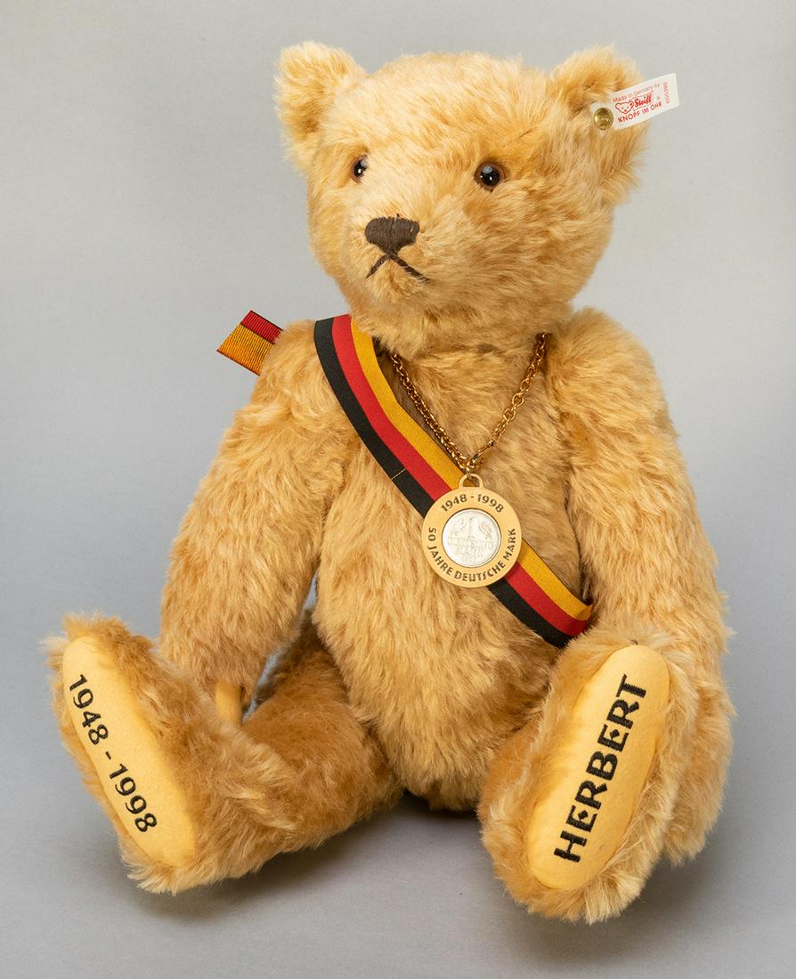 Steiff “Herbert” 1948-1998 Anniversary: Steiff “Herbert” 1948-1998 Anniversary Teddy Bear. 1999. Edition of 1,500. EAN 655395. With sash and commemorative coin necklace. Golden brown mohair. Height 18”.
