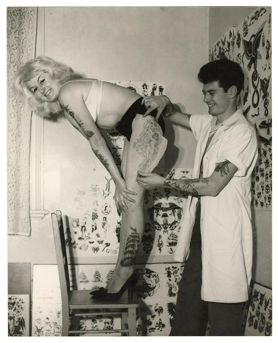 [Tattoo] Ray, Cindy (Bev Nicholas). Photograph of Cindy: [Tattoo] Ray, Cindy (Bev Nicholas). Photograph of Cindy Ray, Australian Tattooed Lady. Australia, 1960s. Glossy full-length pin-up style photograph of Ray in tattoo studio. 10 x 8”. Ray’s 