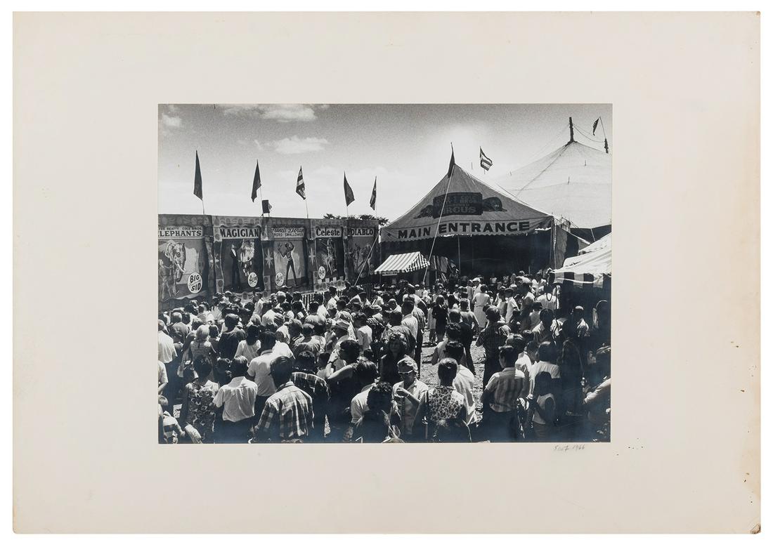 Clyde Beatty-Cole Bros. Midway. Pittsfield, MA, 1966.: Clyde Beatty-Cole Bros. Midway. Pittsfield, MA, 1966. Original matte-finish gelatin print on photographer’s mount, dated 1966 and initialed EWF. A crowd gathers on the midway, outside a white to
