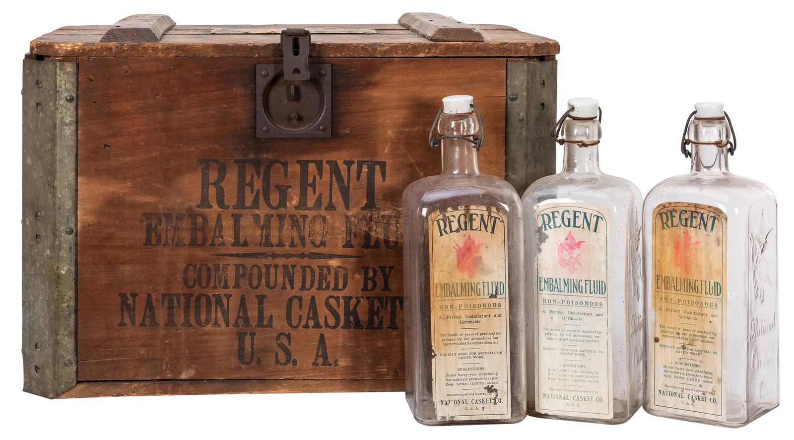 National Casket Co. “Regent” Embalming Fluid Crate with: National Casket Co. “Regent” Embalming Fluid Crate with Bottles. Heavy wooden and metal shipping crate with nine embossed clear glass bottles, some retaining paper labels and porcelain sto