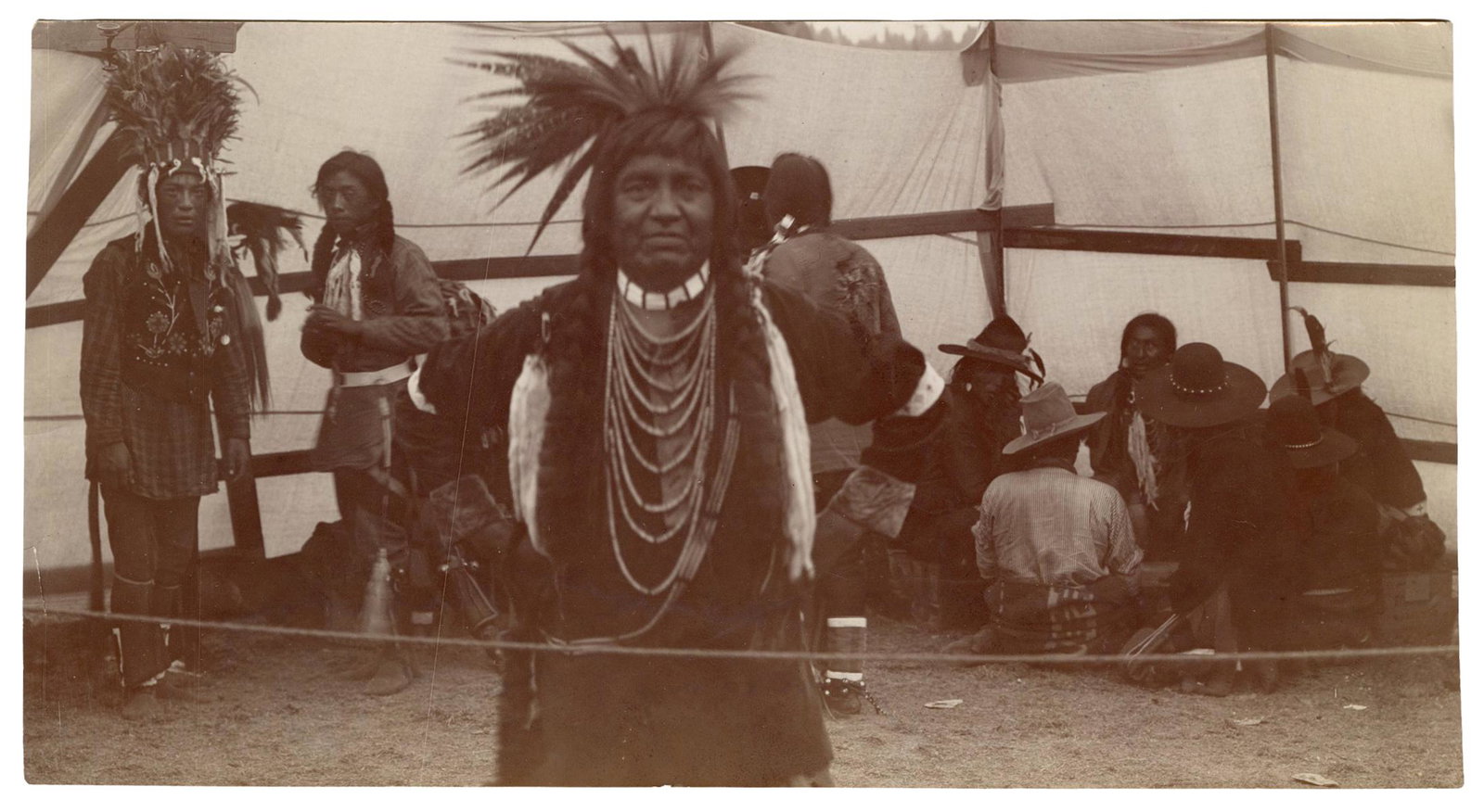 [Native American] Spokane Area Indians Gambling: [Native American] Spokane Area Indians Gambling Photograph. Circa 1900s. Photograph of Native Americans, stamped by August Wolf, Spokane, Wash., on verso, with notation “Indians in holiday garb at g