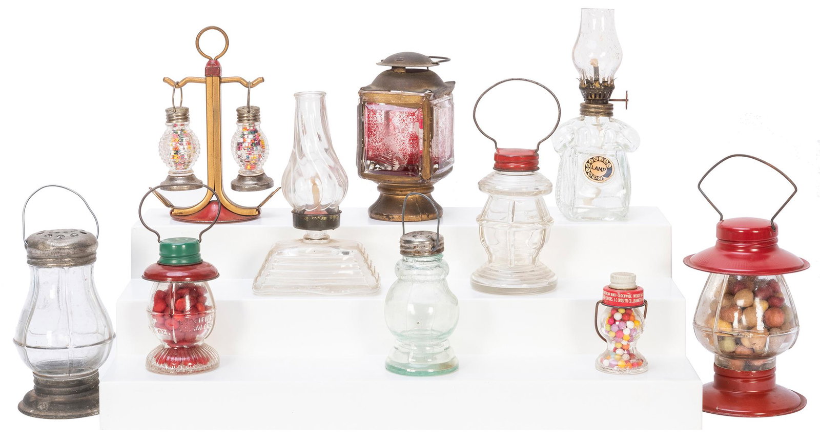 Group of 10 Glass Lantern or Oil Lamp Candy Containers.: Group of 10 Glass Lantern or Oil Lamp Candy Containers. Several containing original candy, most with metal toppers. Largest height 5”. Condition general very good.