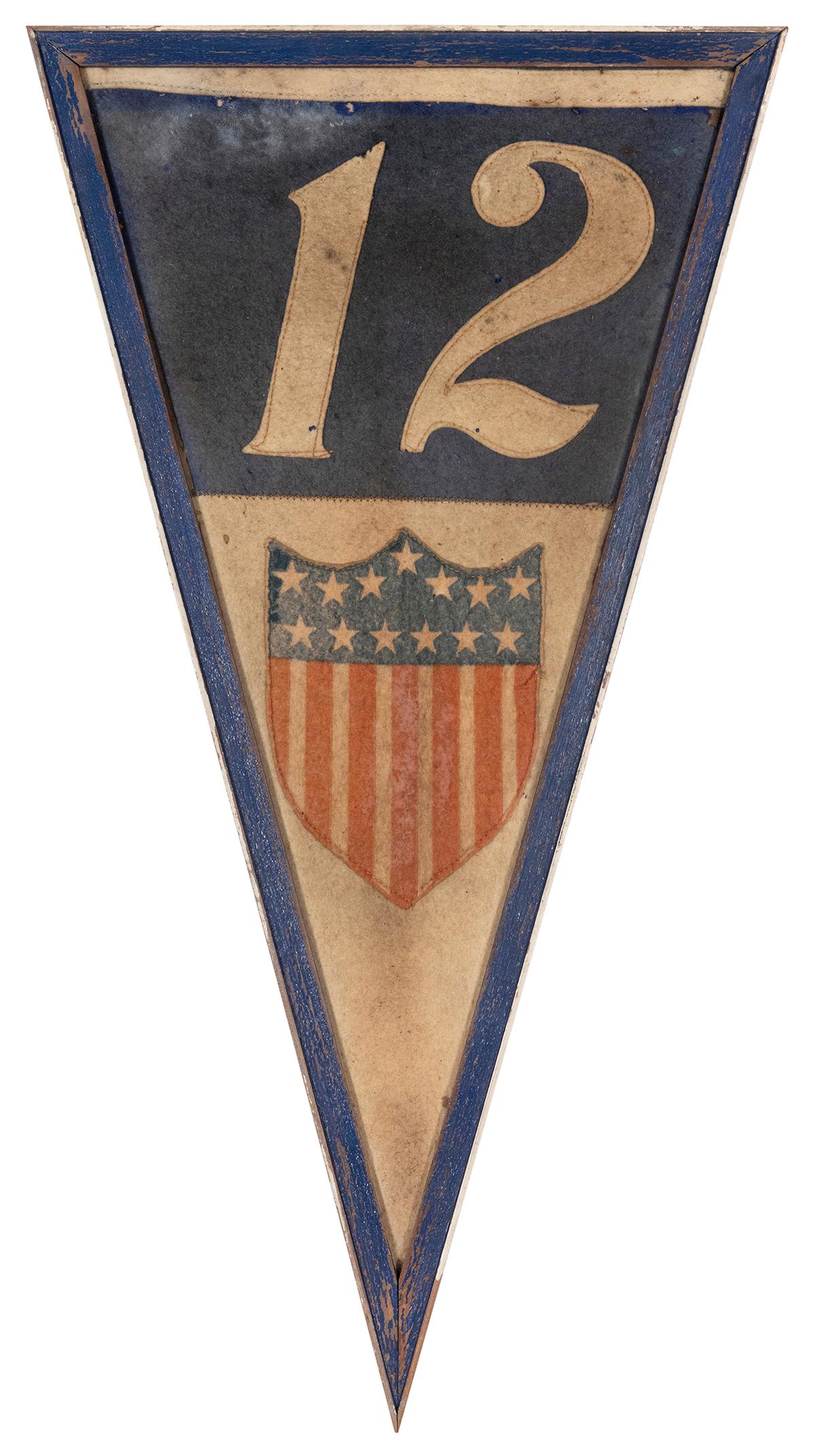 American Military Pennant. Circa 1920s. Depicts: American Military Pennant. Circa 1920s. Depicts American shield with thirteen stars, thirteen stripes. Large number 12 in white against a blue background above. Length 24”. Framed.