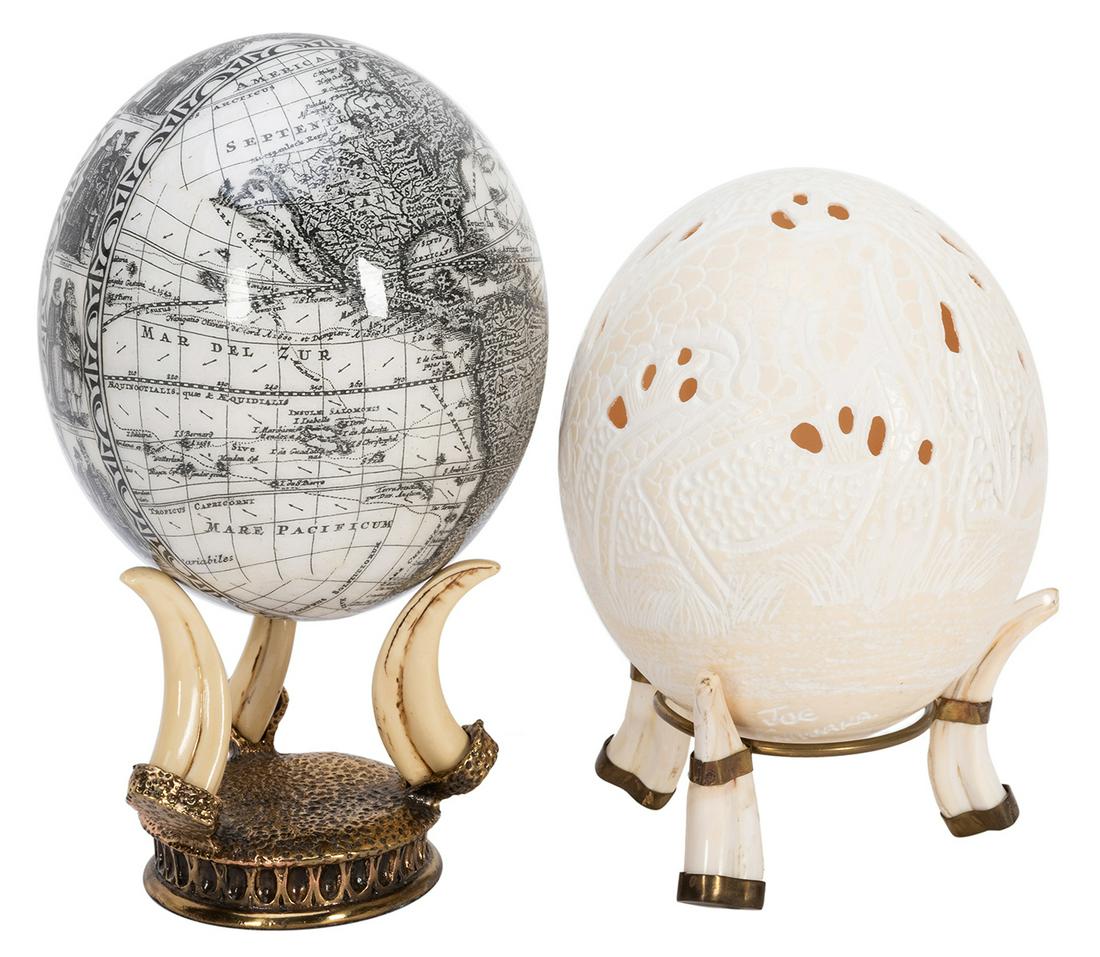 Pair of Ostrich Eggs. Including one carved and signed: Pair of Ostrich Eggs. Including one carved and signed by Joe Chiwaka; the other lithographed with an antique map. Both with stands. Height of eggs, 6”.
