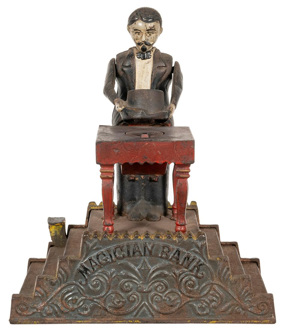 Magician Mechanical Bank. J.E. Stevens, patented Jan.: Magician Mechanical Bank. J.E. Stevens, patented Jan. 22, 1901. Painted cast iron bank in the form of a conjurer behind his table, holding a top hat between his hands. Coins placed under the hat vanis