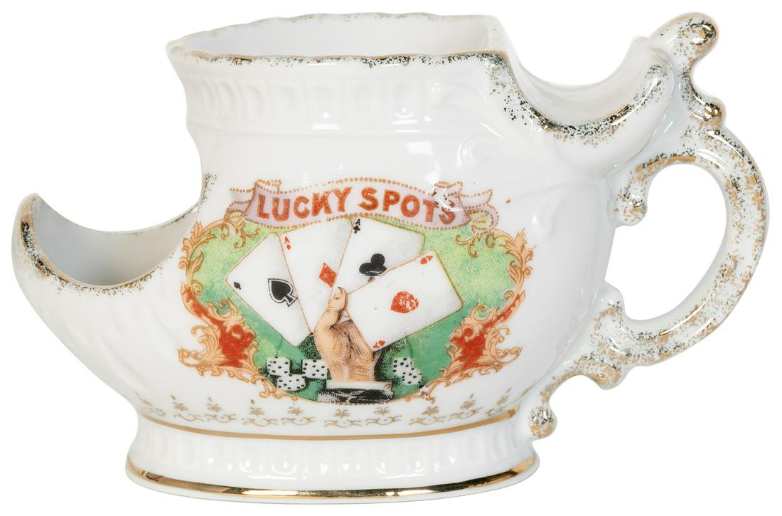 “Lucky Spots” Scuttle Shaving Mug.: “Lucky Spots” Scuttle Shaving Mug. Gambling-themed porcelain shaving mug with four-ace and dice design on one side, violet floral design on opposite, with gilt accents. 4 x 6 ½ x 3 &#