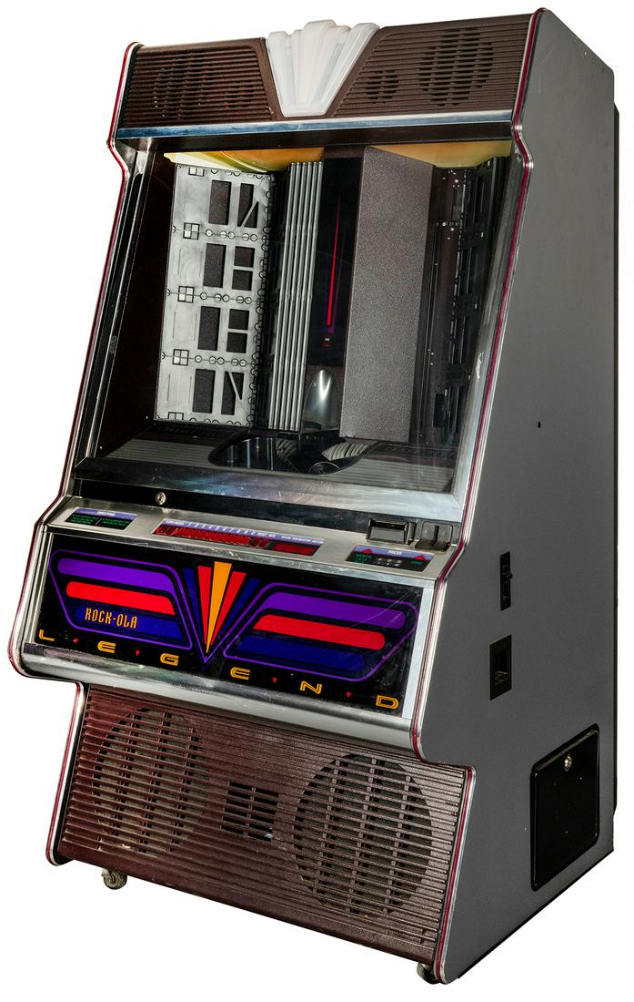 Rock-Ola Mfg. Corp. 6000X Legend CD Jukebox. Torrance,: Rock-Ola Mfg. Corp. 6000X Legend CD Jukebox. Torrance, CA, ca. 1990s. 100-CD capacity. Accepts bills, coins. 35 x 63 x 28”. Key included. Lights up. Third party transportation required.