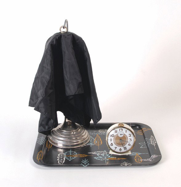 Vanishing Alarm Clock. Petrie & Lewis, ca. 1953.: Vanishing Alarm Clock. New Haven, Petrie & Lewis, ca. 1953. The magician covers an alarm clock with a handkerchief and hangs it from a metal stand. The clock can be heard to ring as it hangs on the st