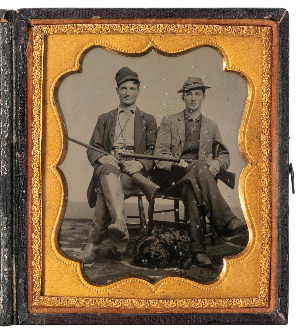 [EARLY PHOTOGRAPHY]. Sixth plate tintype of hunters with do...: [EARLY PHOTOGRAPHY]. Sixth plate tintype of hunters with dog. Circa 1860s. Portrait of two seated young men with shotguns wearing hats and one with tall game-hunting boots, a black Labrador at their f