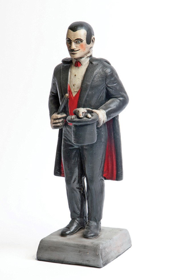 Statuette of a magician. California, Suds 1974: [Statuette] Statuette of a magician. California, Suds, 1974. Handsome plaster statuette of a magician garbed in a tuxedo and cape, and carrying a top hat that a rabbit is peeking out of. 18" high. Goo