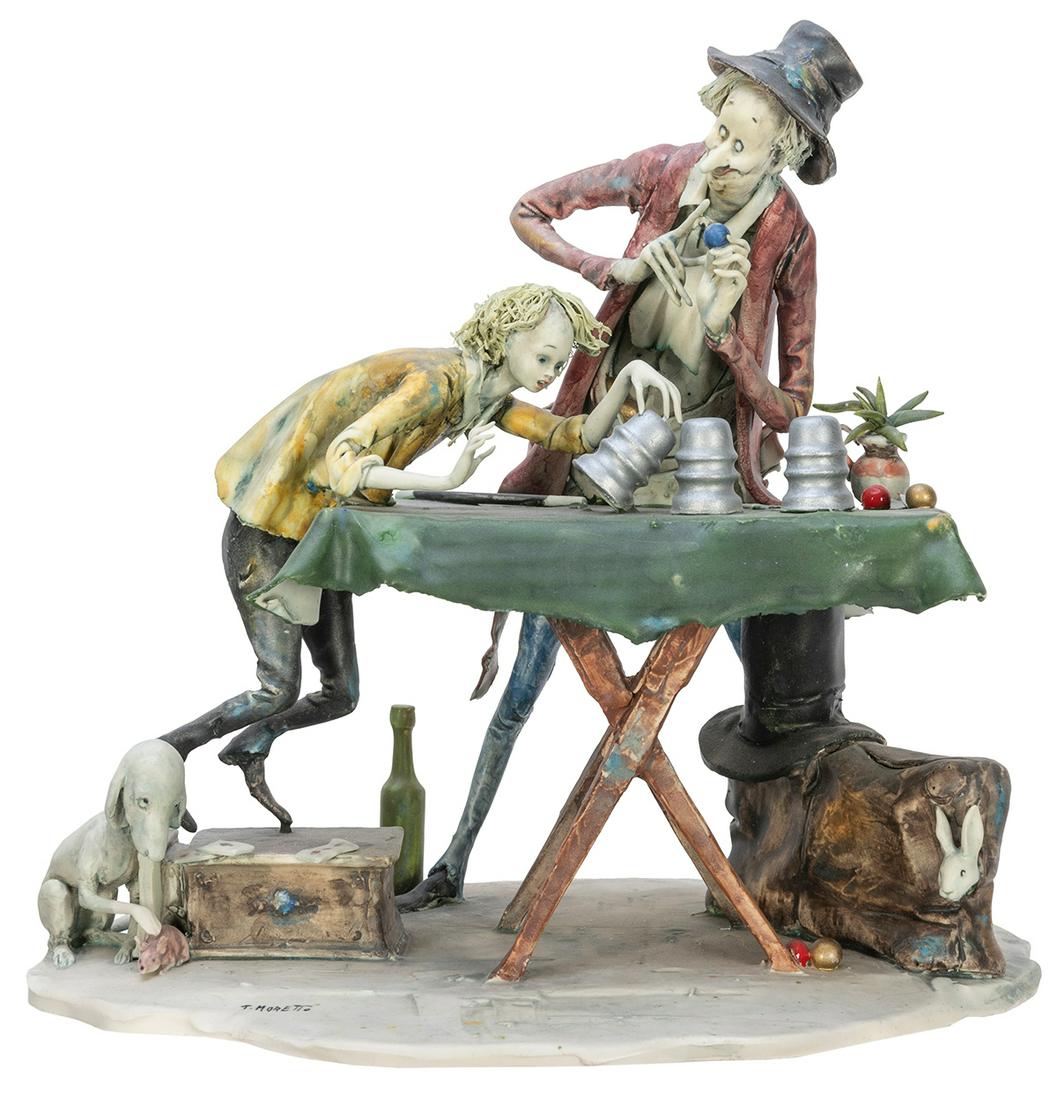 MORETTO, Toni (1929-2011). Cups and Balls Magician with Spe...: MORETTO, Toni (1929-2011). Cups and Balls Magician with Spectator. Italy, ca. 1990s. Detailed ceramic sculpture depicts an itinerant magician at a table, performing the Cups and Balls, a satchel and s