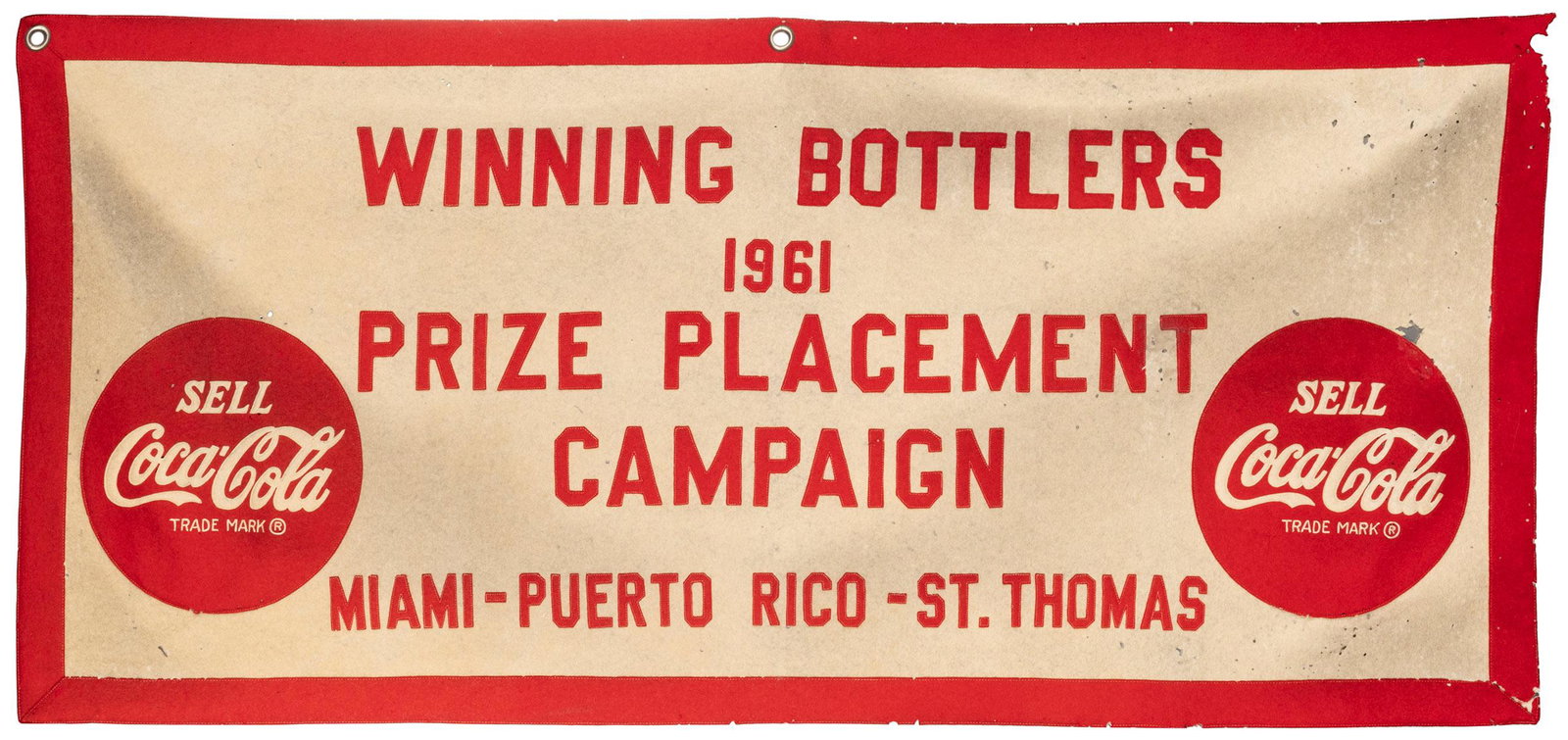 Coca-Cola Winning Bottlers 1961 Prize Placement Campaign cloth banner. Cloth banner with sewn-on: Coca-Cola Winning Bottlers 1961 Prize Placement Campaign cloth banner. Cloth banner with sewn-on cloth borders, Coca-Cola symbols, and lettering. Approximately 26 x 55”. Soiled, multiple small h