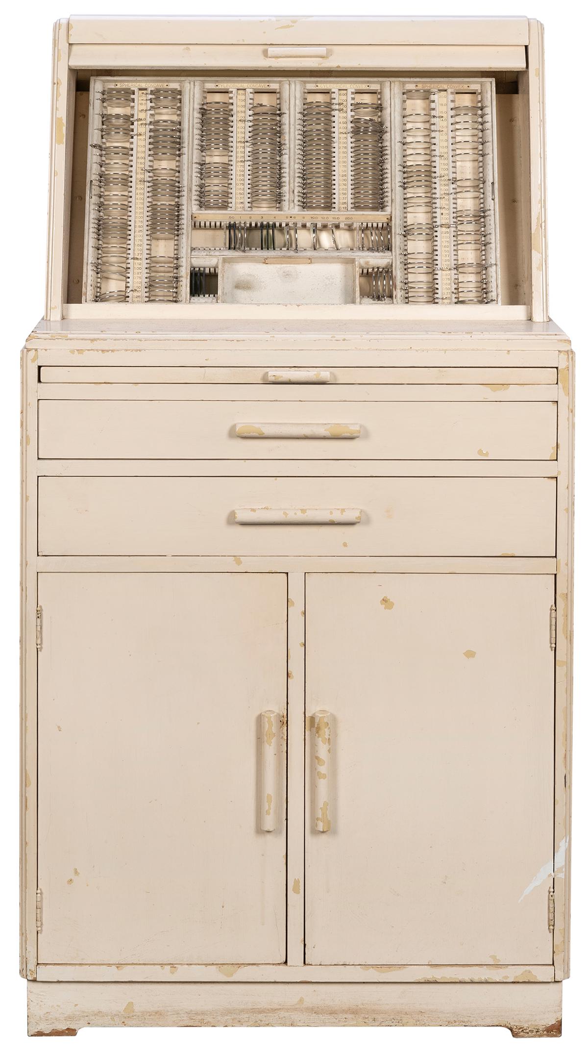 Vintage Wooden Optometrist’s Cabinet. Tan-painted wooden cabinet with numerous lenses. Top (1 of 2)