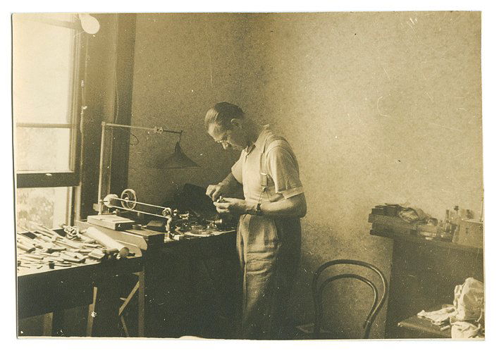 Two photographs of John Martin in his workshop: Martin, John. Two photographs of John Martin in his workshop. In one image, Martin crouches over his workbench, in the other, he demonstrates a holdout device known in the trade as “Cardini’s Thir