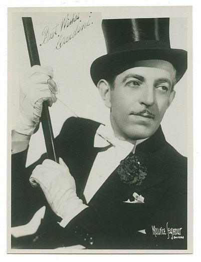 Seymour, Maurice. “Fan” portrait of Cardini, inscribed: Seymour, Maurice. “Fan” portrait of Cardini, inscribed and signed. Chicago, ca. 1934. Half-length portrait of Cardini, monocle and cane prominent in the image. 5 x 7”. With original envelope. In