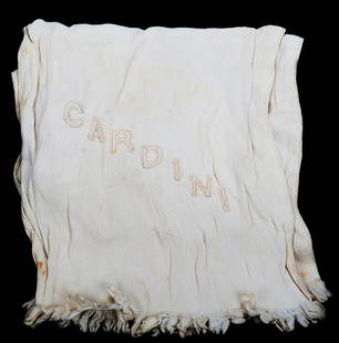 Cardini’s embroidered silk scarf.: Cardini’s embroidered silk scarf. Being a gentleman’s white silk scarf worn with tie and tails, and embroidered with the name “Cardini” in block capital letters near one end. 7 ½ x 40 ½”.